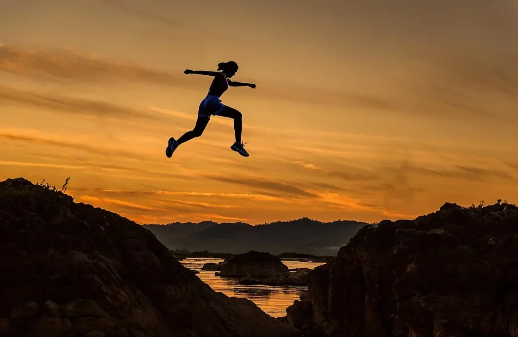 Femme sportive qui saute d'une rive vers l'autre. Cette image illustre l'énergie de l'année personnelle 1 pour calculer et comprendre les années personnelles en numérologie.