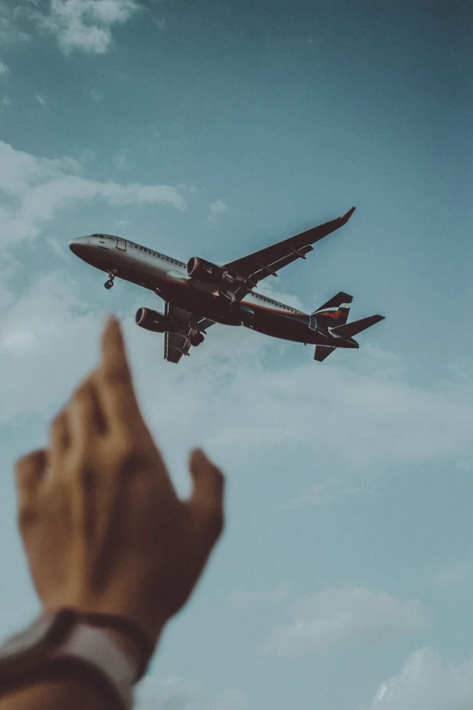 Main tendue vers un avion dans le ciel. Peur de l'avion, comment l'accompagner avec l'hypnose ?