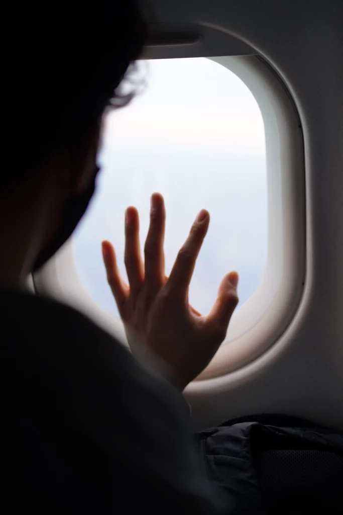 Main posée en signe de détresse sur le hublot d'un avion.