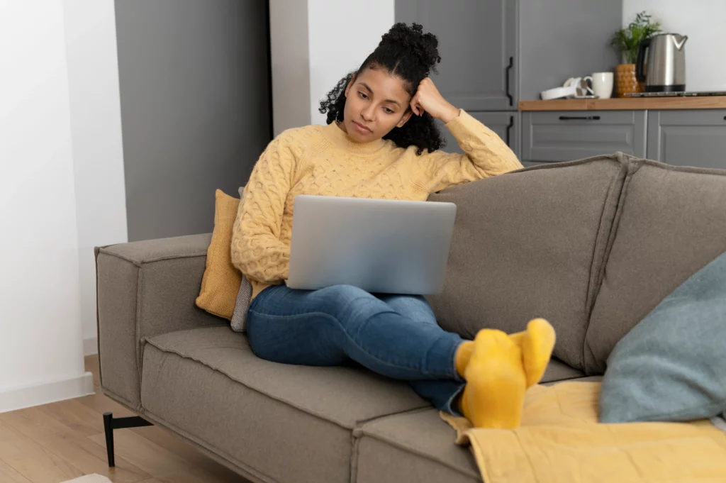 Hypnose à distance : est-ce vraiment aussi efficace qu'en cabinet ? Une jeune femme, semi-allongée sur son canapé.